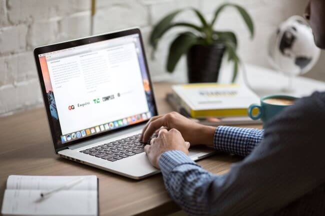 Person typing on laptop with cup of coffee
