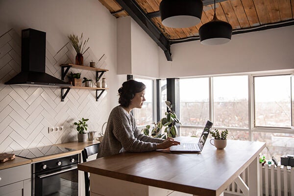 Woman at kitchen island on a laptop