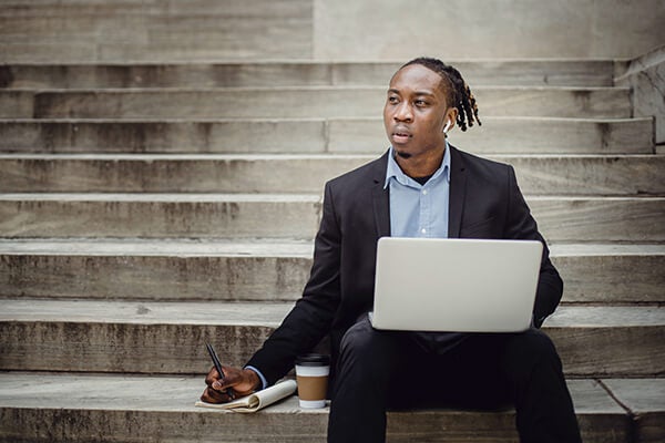 African American man with a laptop taking notes