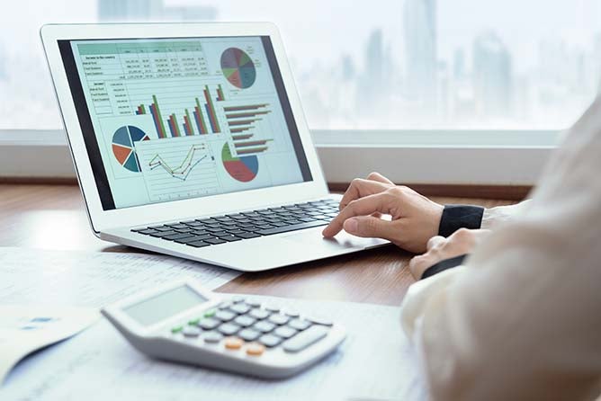 A laptop displays some spreadsheet graphs and charts.