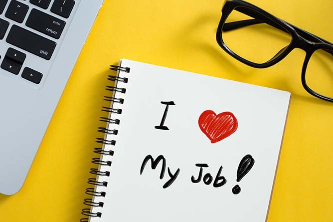 Conceptual image of a desk with a notepad displaying a message saying, "I Love My Job."