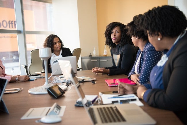 Women sitting around board room table talking