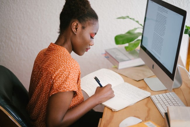 Girl writing in notebook at computer - when can I start online degree