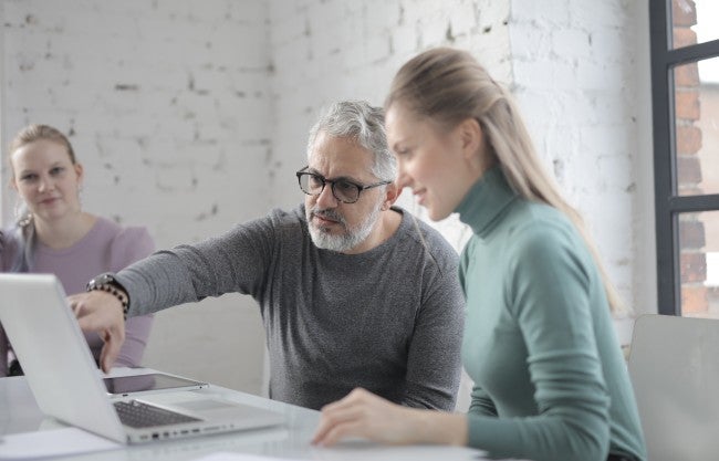 Older man looking at computer with female colleagues