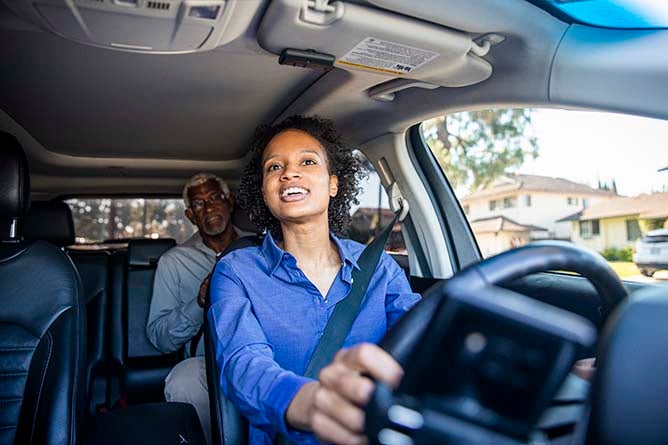 A young woman drives an older man to his destination.