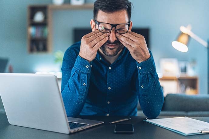 A tired business man rubs his eyes after a long day.