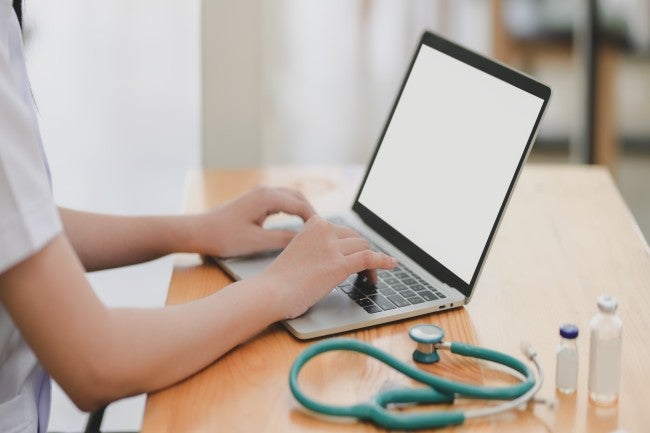 Nurse typing on computer next to stethoscope
