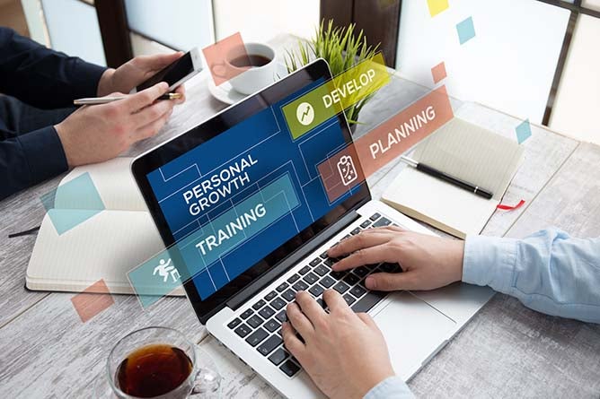 A man types on a latptop with a personal growth plan displayed on-screen.