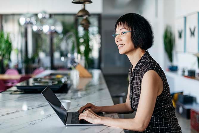 A woman sitting at a laptop with a smile on her face.