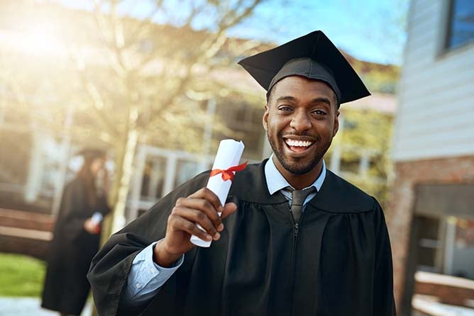 A happy young graduate holds up his diploma.