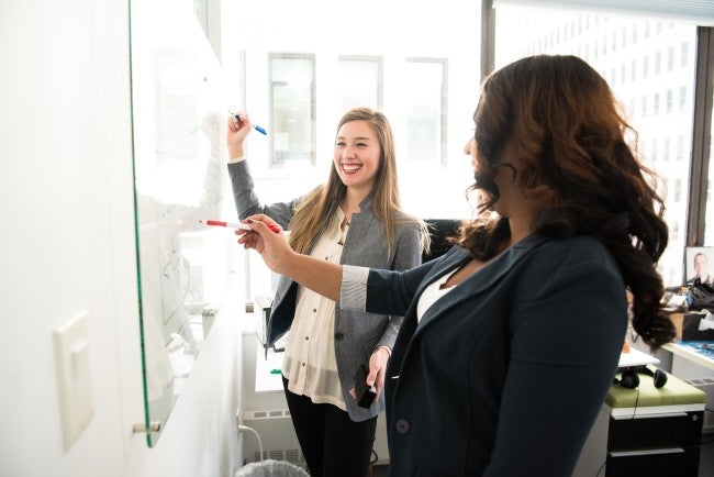 Two women at white board doing curriculum planning