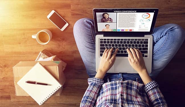Overhead photo of person sitting cross-legged with a laptop, coffee, and cell phone.