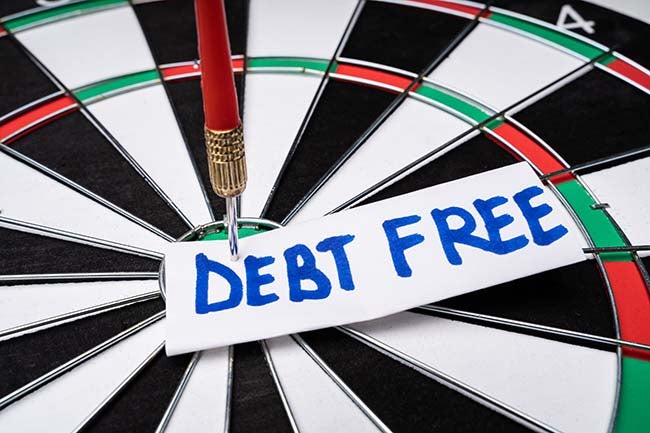 Dart board with a sticky note displaying the words "debt free."
