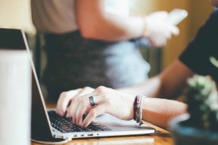 person's hands typing on a laptop