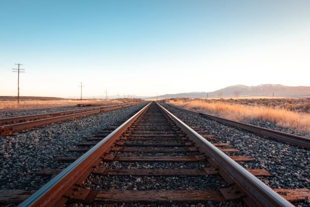 Train track leading into the distance of a sunny desert
