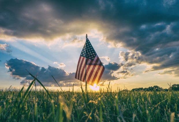 US flag in field at sunset