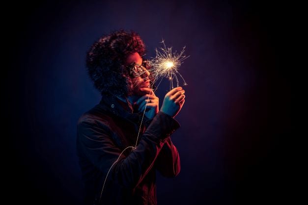 man with glasses holding a sparkler and thinking