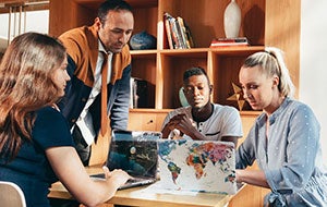A group of teachers gathered around laptops