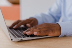 man with hands on laptop keyboard