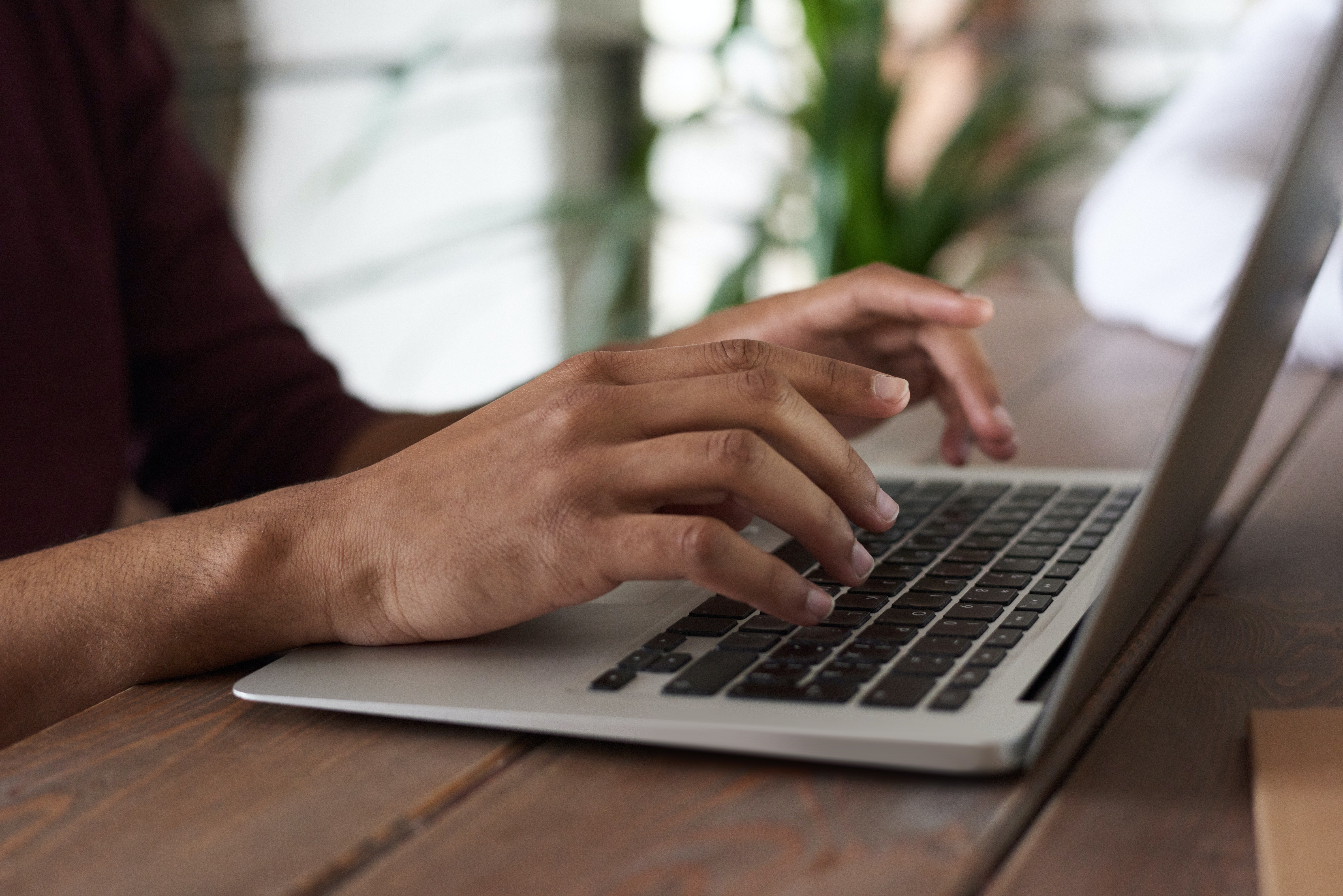 person's hands typing on a laptop