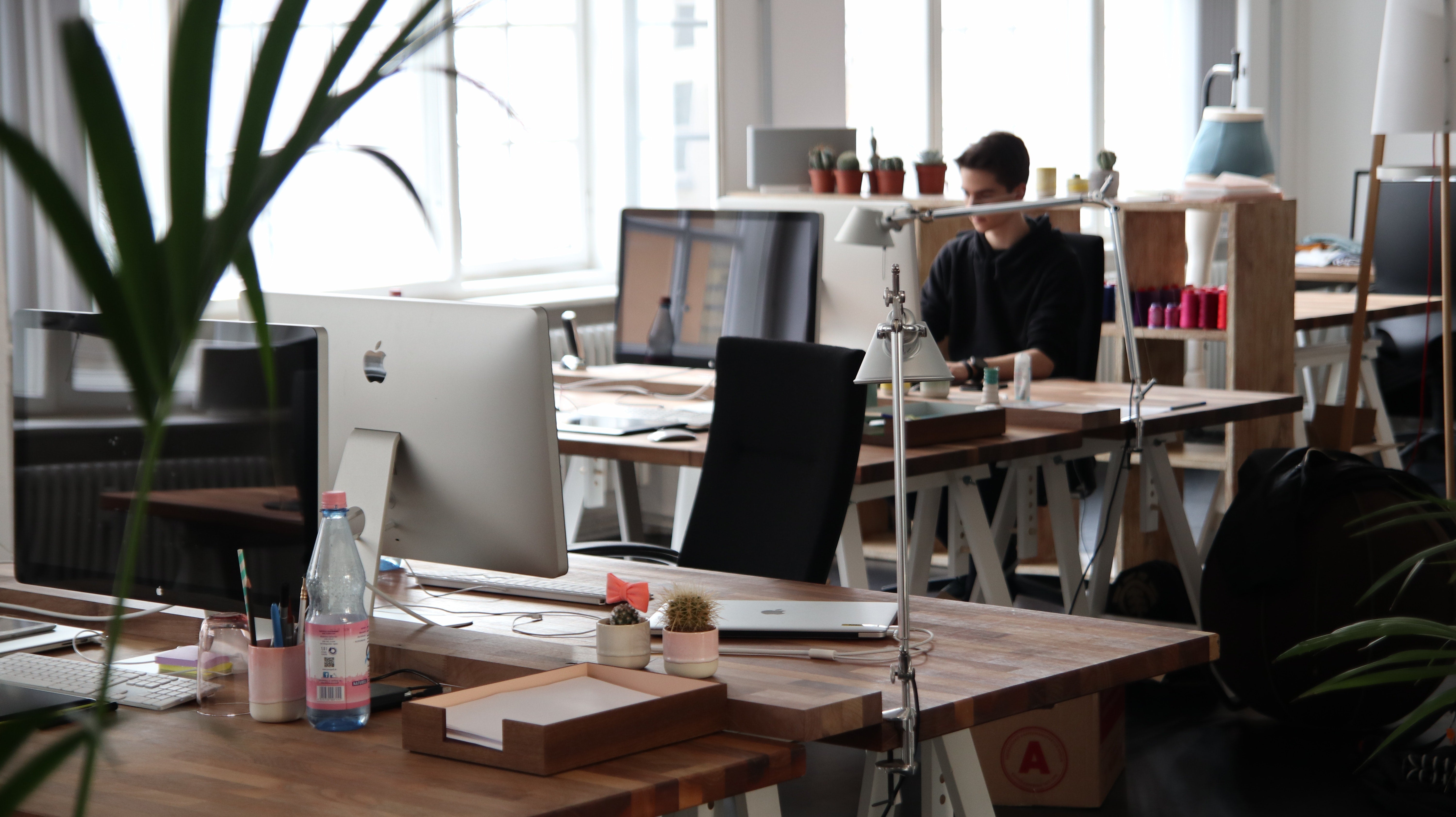 empty chair at a desk with a person sitting at a desk behind it