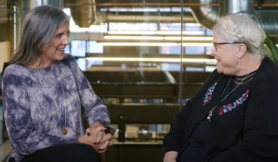 Marni Baker Stein and Michelle Jungbauer sitting, facing each other and talking