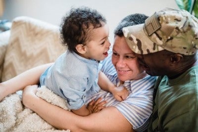 Two adults, one in United States military dress, and one baby