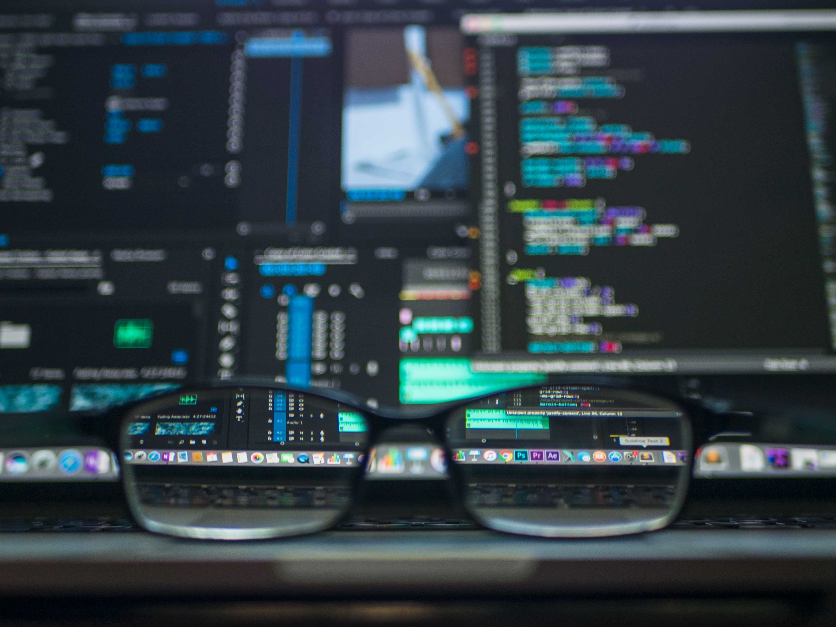 a pair of eyeglasses highlighting a computer with code