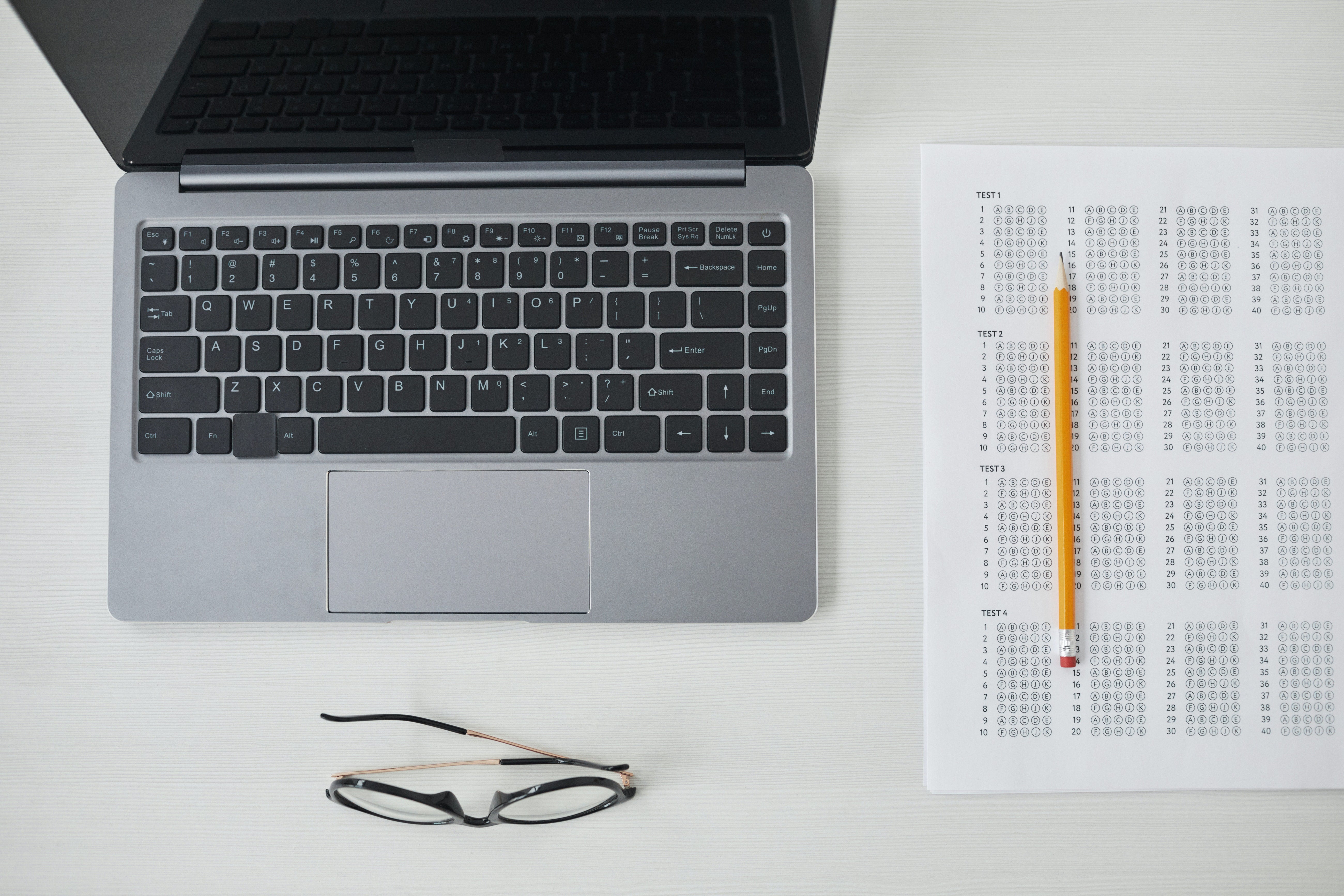 laptop sitting next to a standardized test sheet