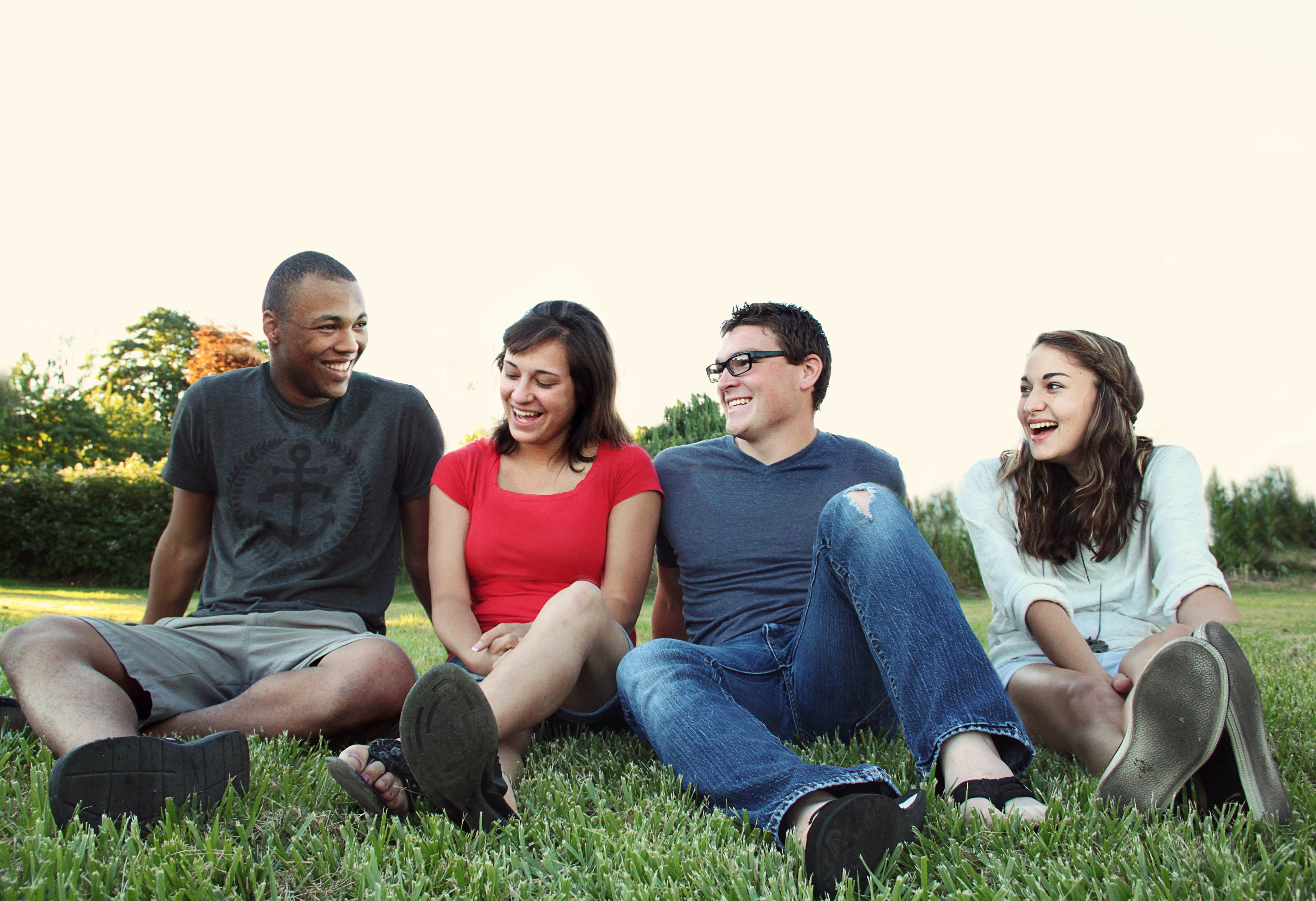 group of young adults sitting outside in the grass