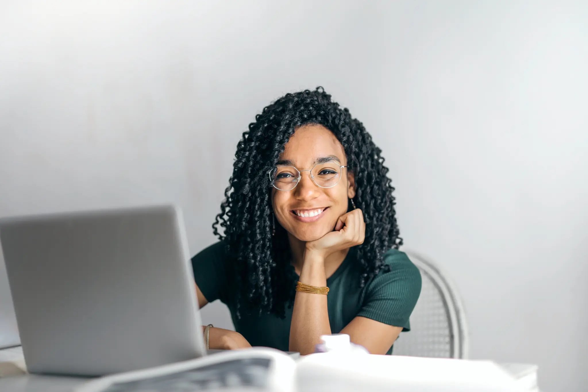 person sitting in front of an open laptop smiling at the camera