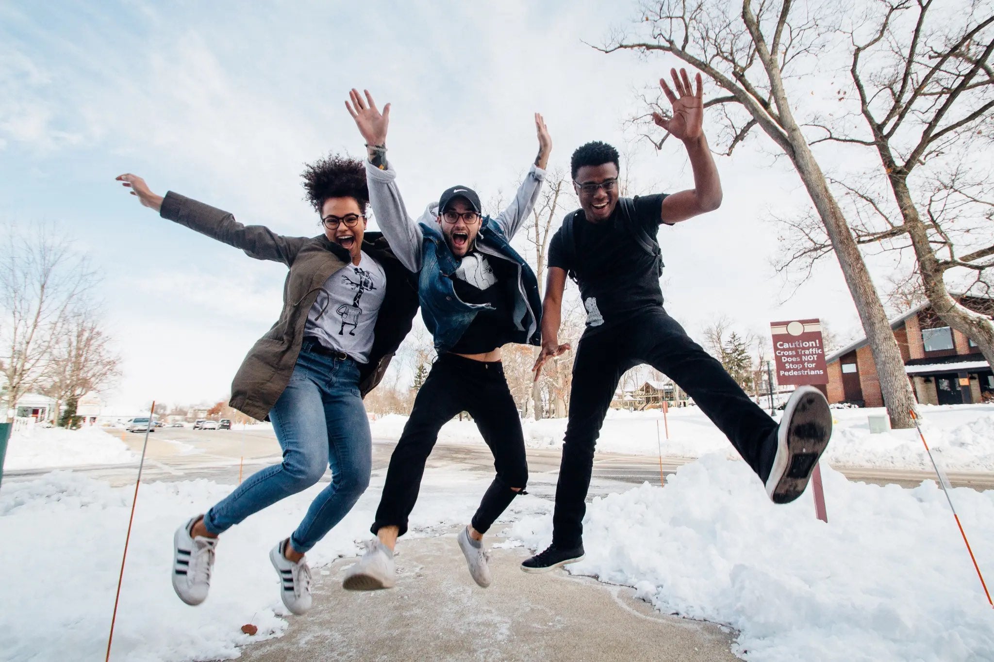 Group of young adults jumping on a snow-covered sidewalk