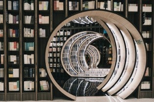 Room full of books with circle passageway to another room full of books