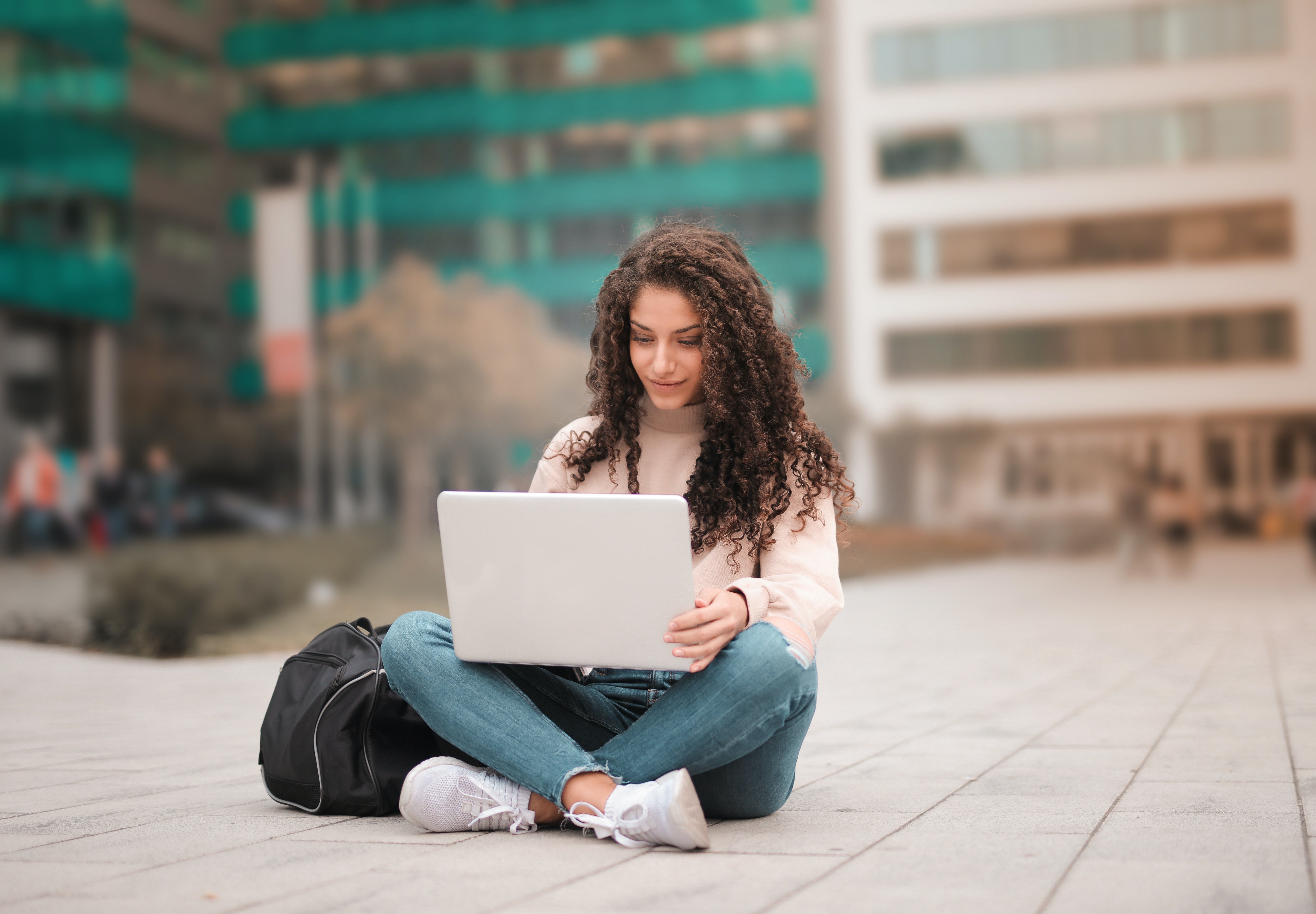 person sitting on a concrete patio with a laptop