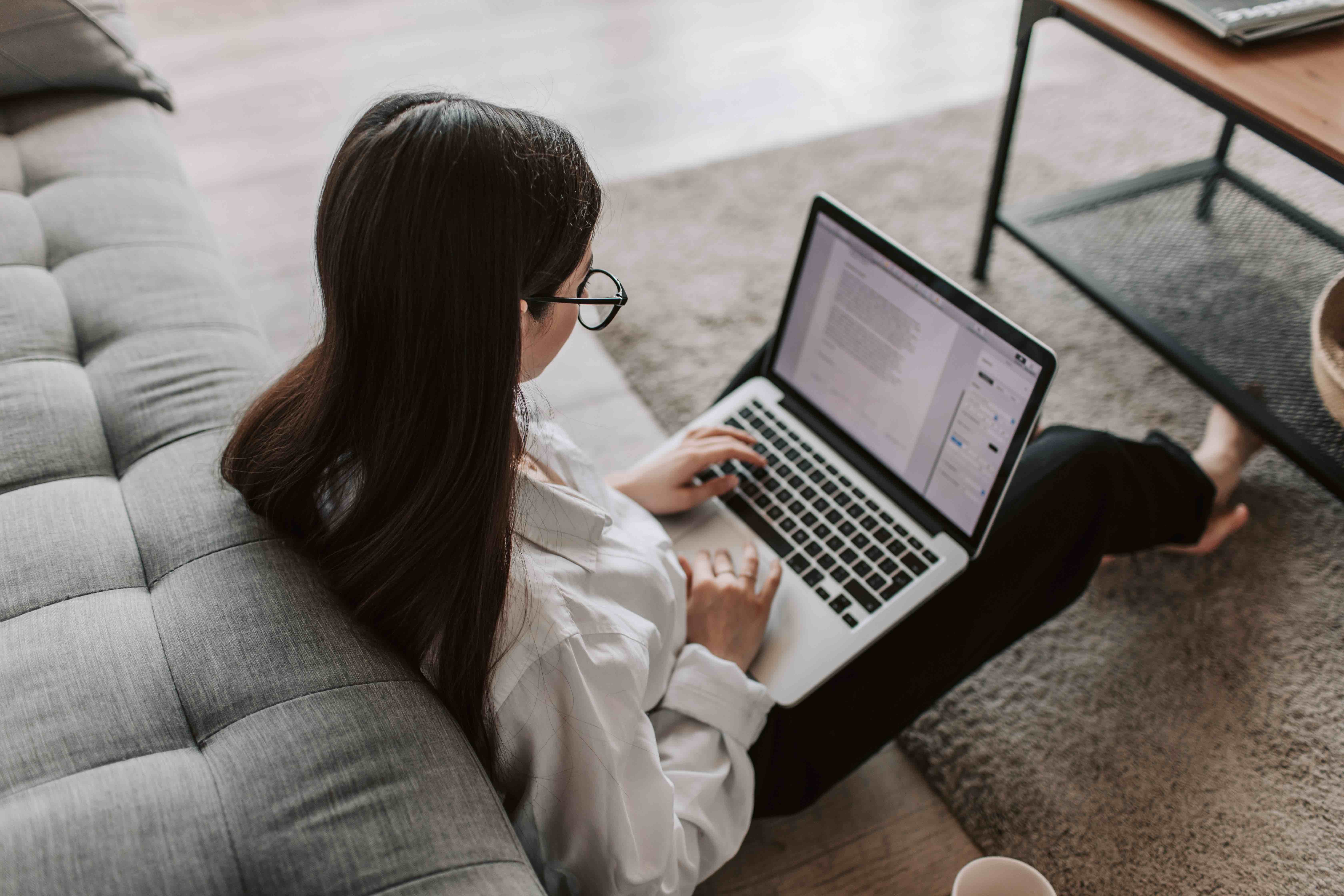 person sitting on the floor looking at a laptop