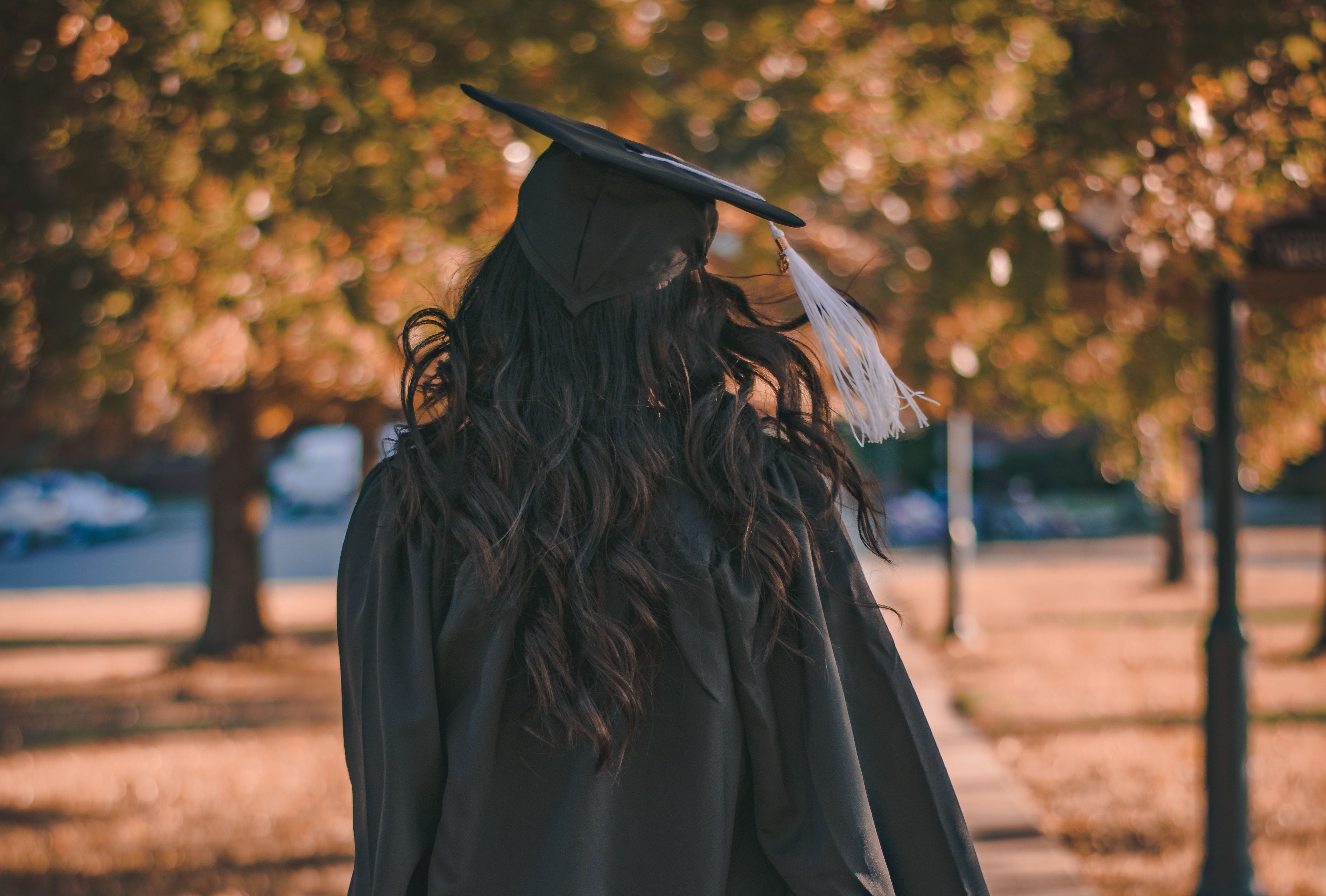 a person walking in a graduate cap and gown