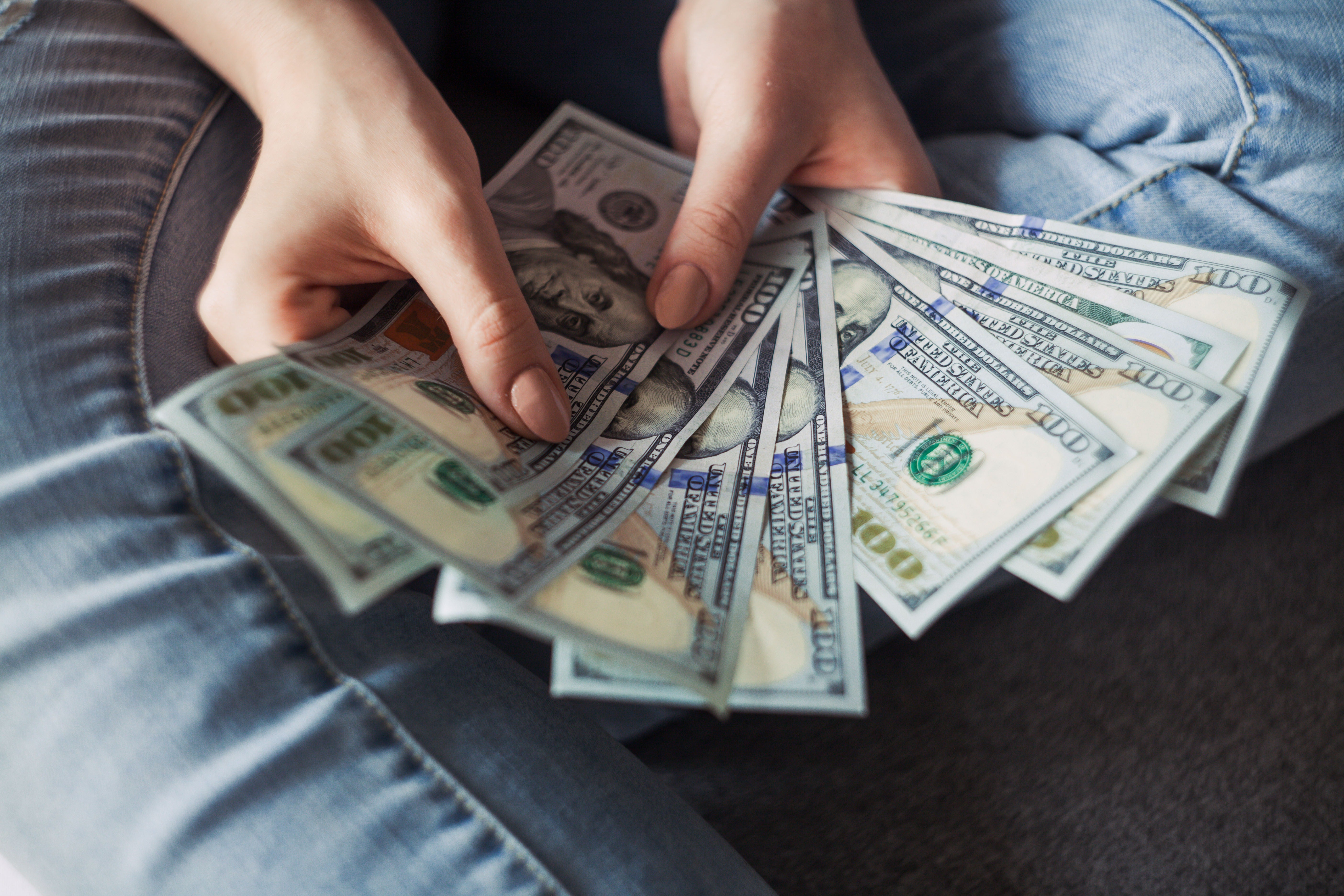 person sitting with while fanning dollar bills