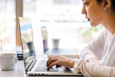 person looking at a screen and typing on a laptop