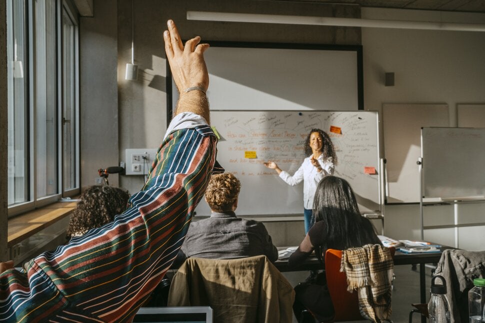 person standing in front of a white board facing a classroom
