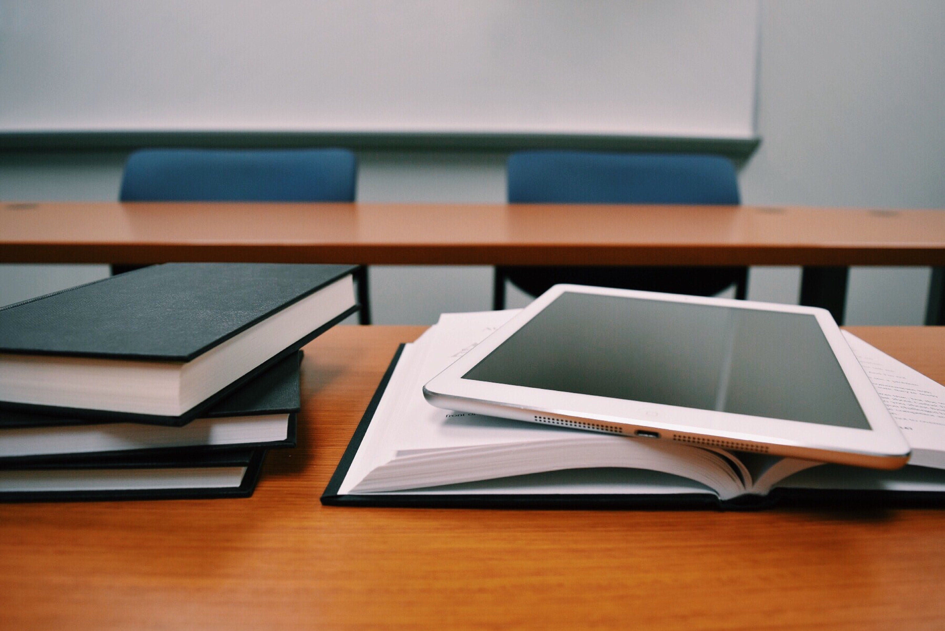 a desk with a stack of books and an ipad on top