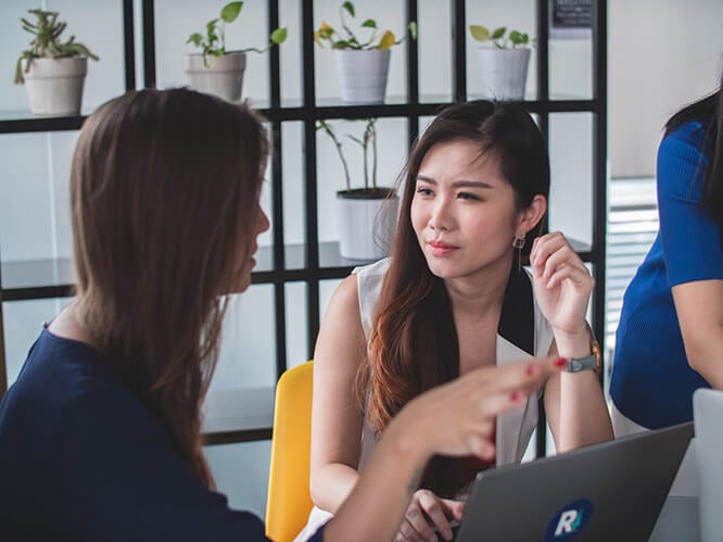 Two women, discussing over a laptop
