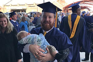 WGU grad holds baby