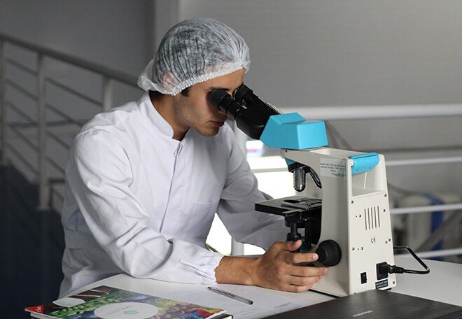 Technician looking thru a microscope