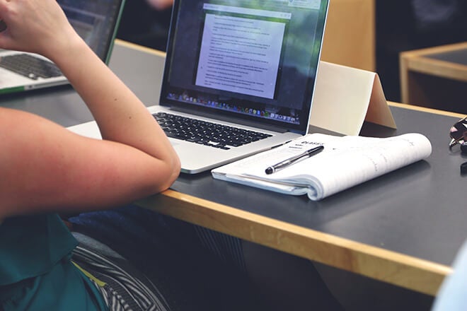 Student using a laptop and notes