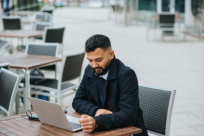 Man on a laptop at an outdoor table