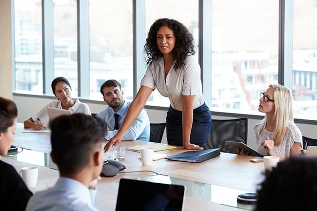 female business professional standing while she leads the meeting