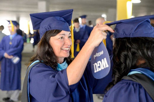 WGU graduate helping student with cap