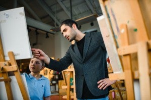 student teacher helping art student