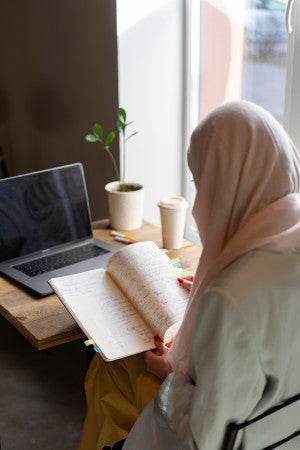 female study reading notes while on computer