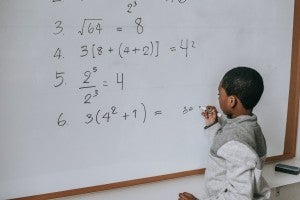 young student working math problem on the board